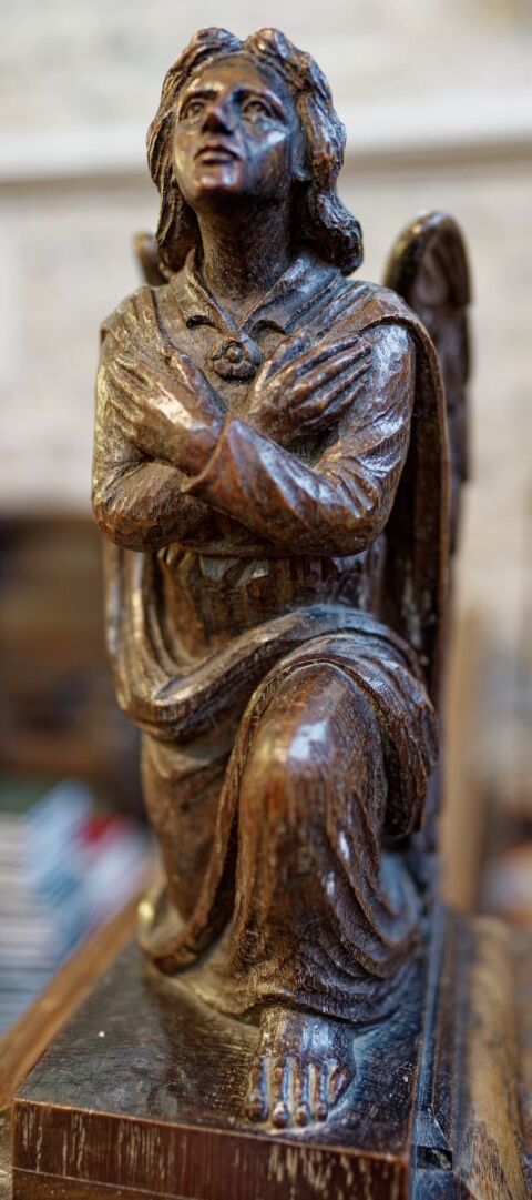 A close up of the side of a wooden angel on the end of the Lady Chapel altar rail in Ottery St Mary church