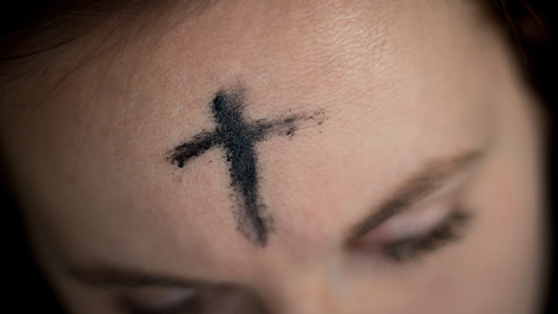A photo of a person with a cross of ash on their forehead