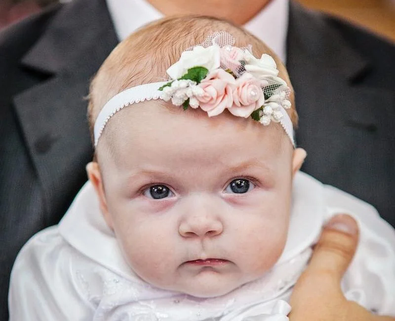 A baby in its father's arms at a baptism service