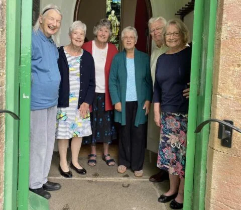 Congregation gathered in the doorway welcoming you at Escot church