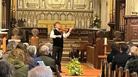 A picture of violinist Joel Munday performing at Ottery St Mary church