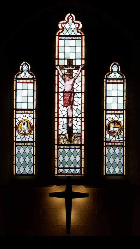 A view of the three panel east window and backlit cross