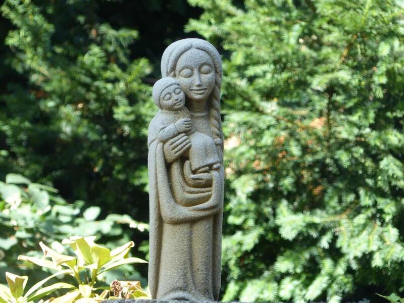 A statue in a churchyard of a mother holding a child