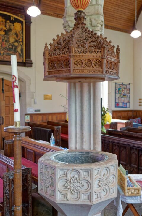 A view of the carved stone font and ornate carved wooden lid at Payhembury church