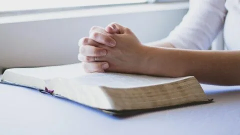 A picture of someone praying with a bible