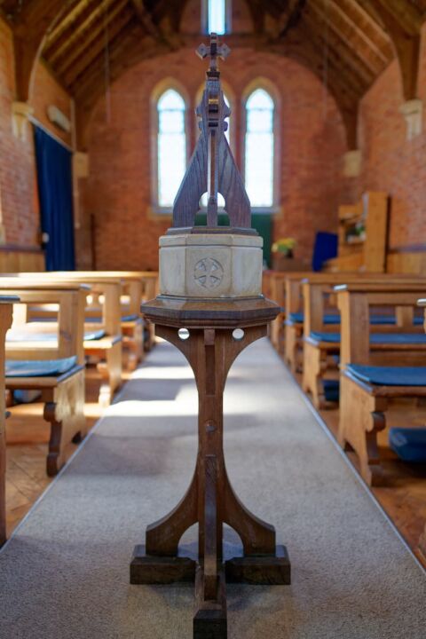 A view of the small moveable font in Wiggaton church with a wooden base and top and tiny stone bowl