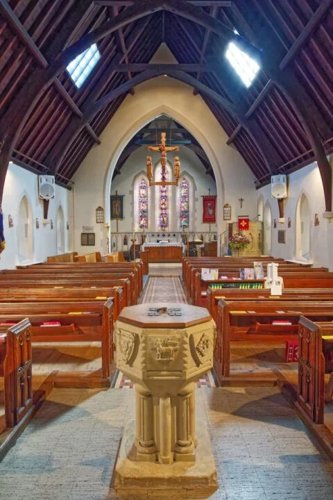 A view down the entire length of West Hill church from the stone font through the nave and pews to the altar